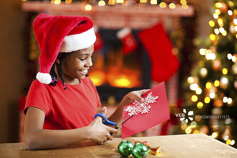 漂亮的女孩在做圣诞卡片。图片素材