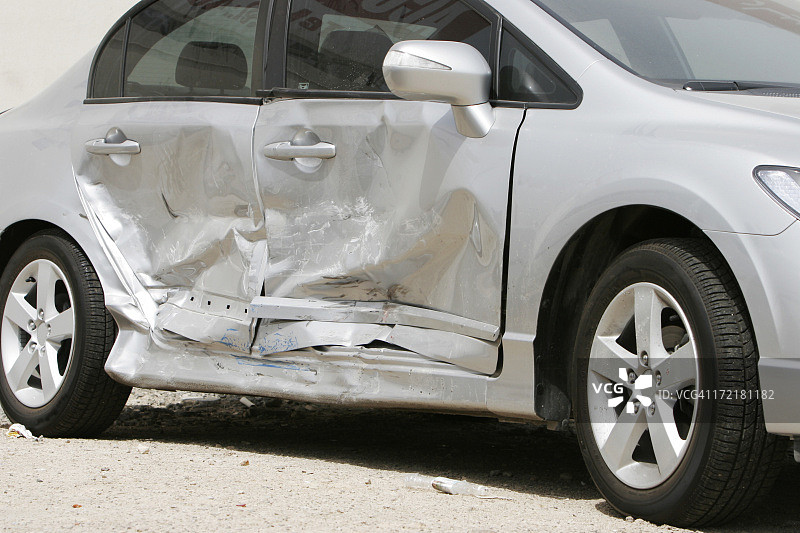 银色汽车，侧面有一个大凹痕，毁坏了两扇门图片素材