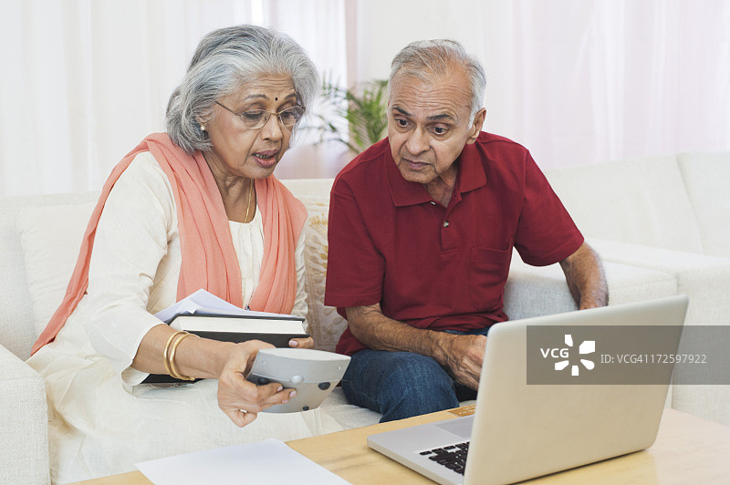 一对老年夫妇坐在笔记本电脑前检查账单图片素材