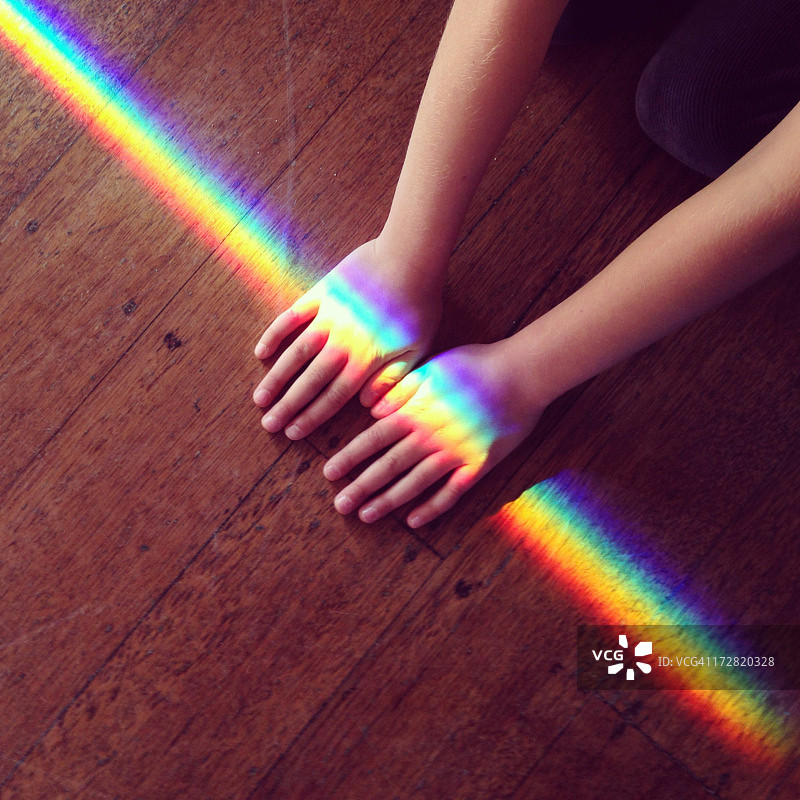 彩虹光交叉着一个孩子的双手在地上图片素材