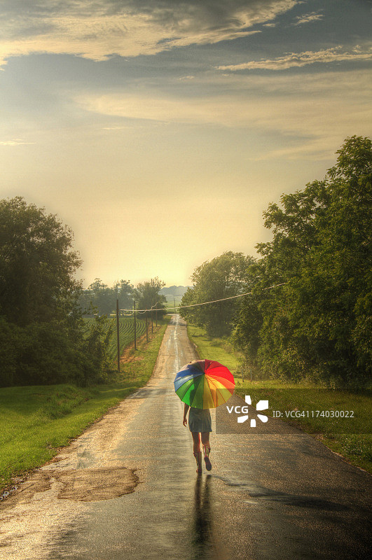 带着彩虹伞走在路上的女人图片素材