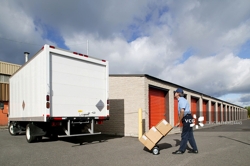 送货员用手推车把箱子搬到卡车上图片素材