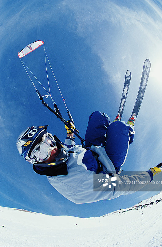 男子表演空中跳跃，同时风筝滑板在雪，低角度的观点图片素材