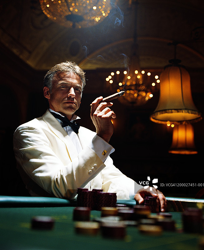 在赌场里穿着晚礼服抽着雪茄的男人，肖像图片素材