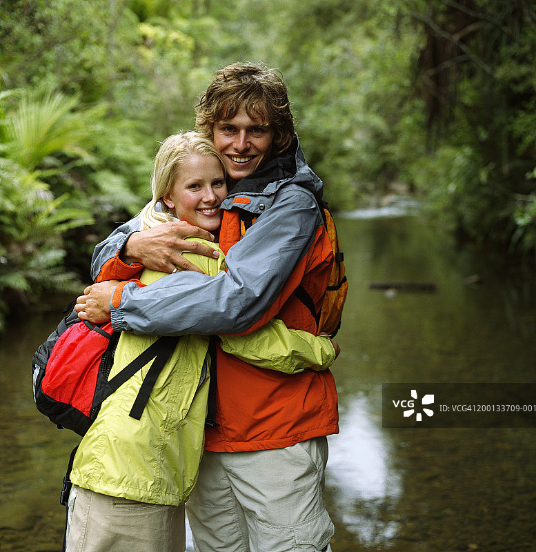 一对年轻夫妇站在溪流中，拥抱在一起图片素材