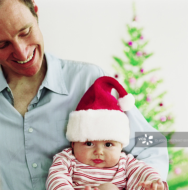 父亲抱着女儿(3-6个月)，宝宝戴着圣诞帽图片素材