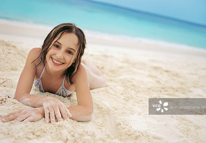 女孩(10-12)躺在沙滩上，肖像(专注于脸)图片素材