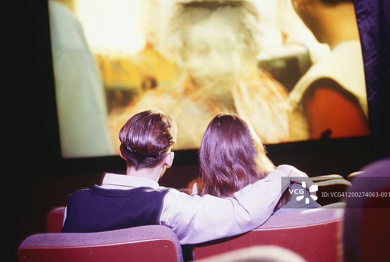 青少年情侣(16-17岁)坐在电影院看电影图片素材