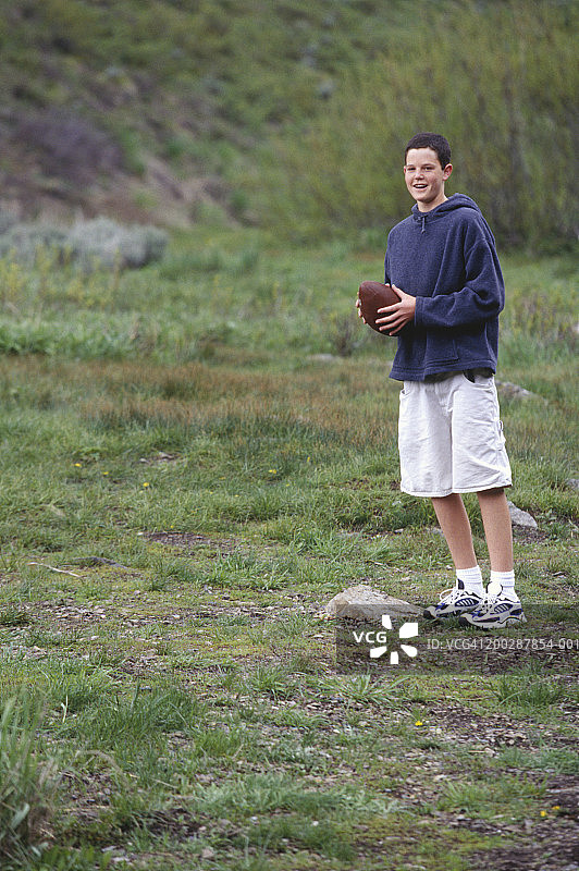 少年(14-15岁)站在球场上，拿着足球图片素材