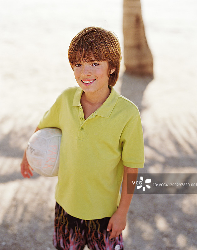 男孩(8-10)拿着球，微笑着，肖像图片素材