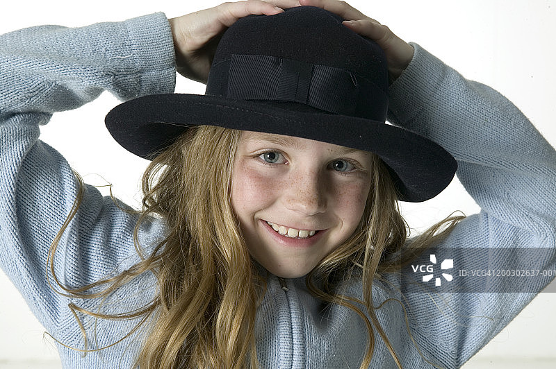 女孩(8-9)戴着帽子，在工作室摆姿势，肖像图片素材