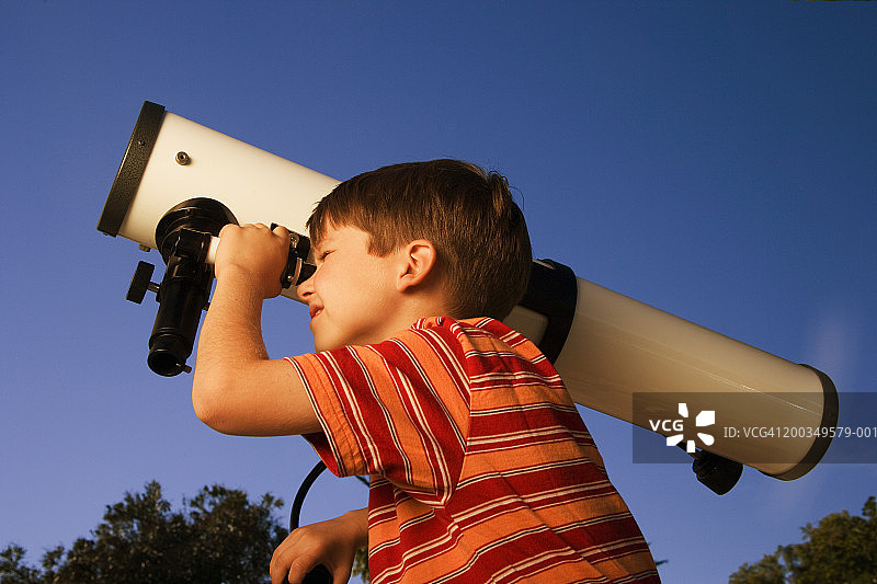 男孩(6-8)通过望远镜看，特写，侧视图，黄昏图片素材