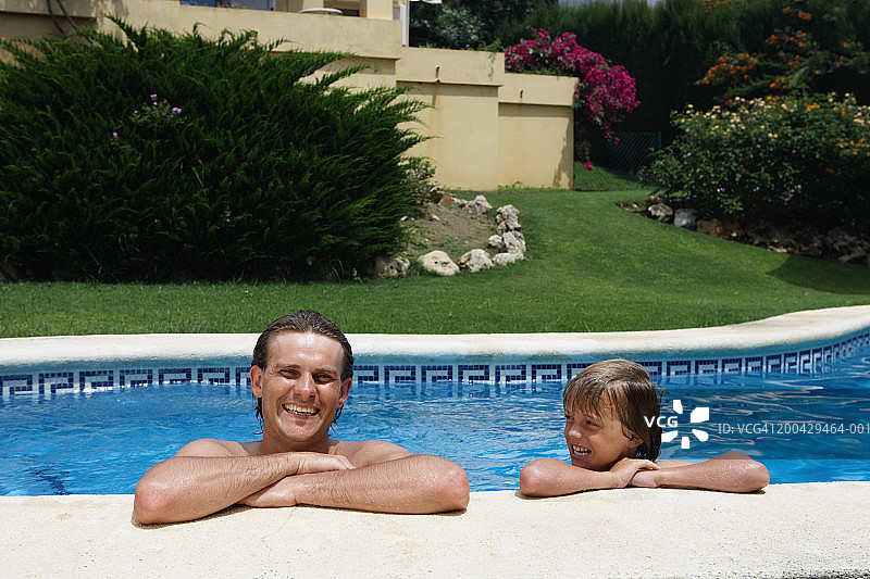 父亲和儿子(8-10)靠在室外游泳池的边缘，男人的肖像图片素材