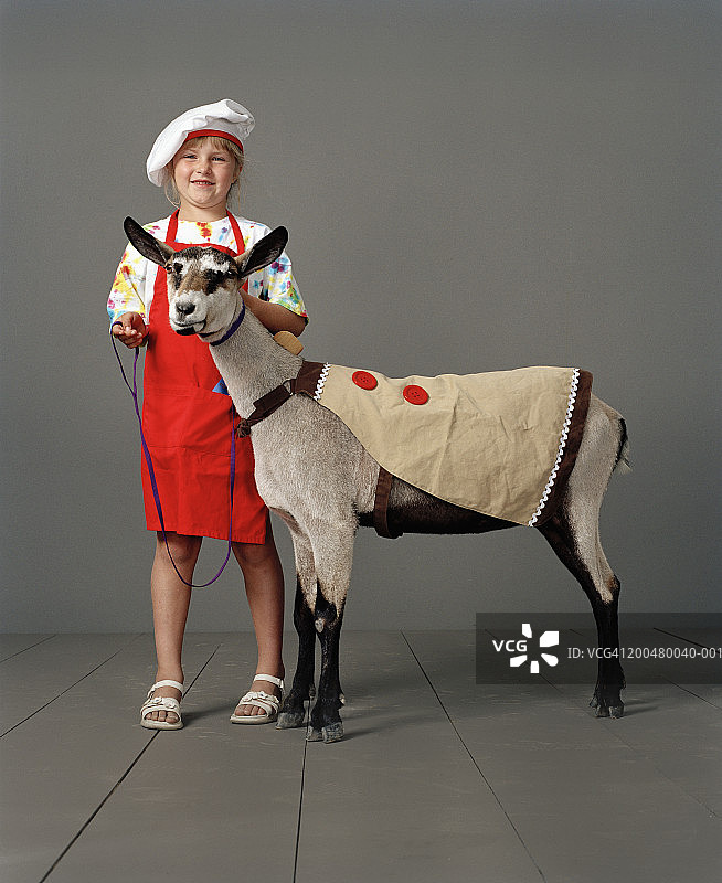 女孩(7-9号)穿着厨师装和山羊，肖像图片素材