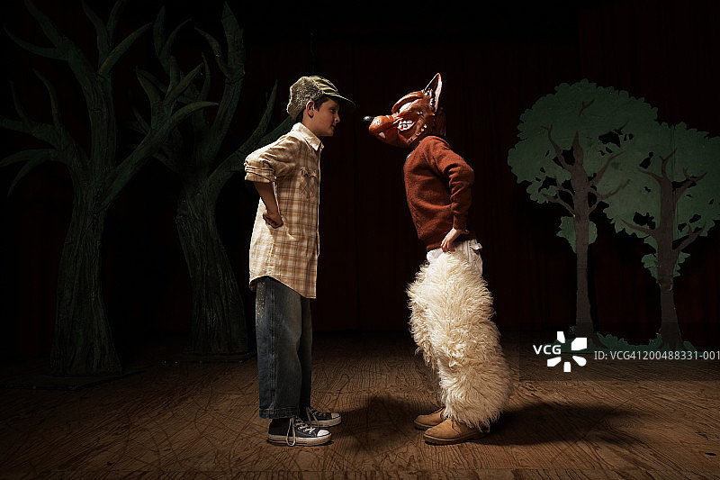 两个男孩(9-11)在舞台上表演，一个男孩面对另一个坏狼图片素材