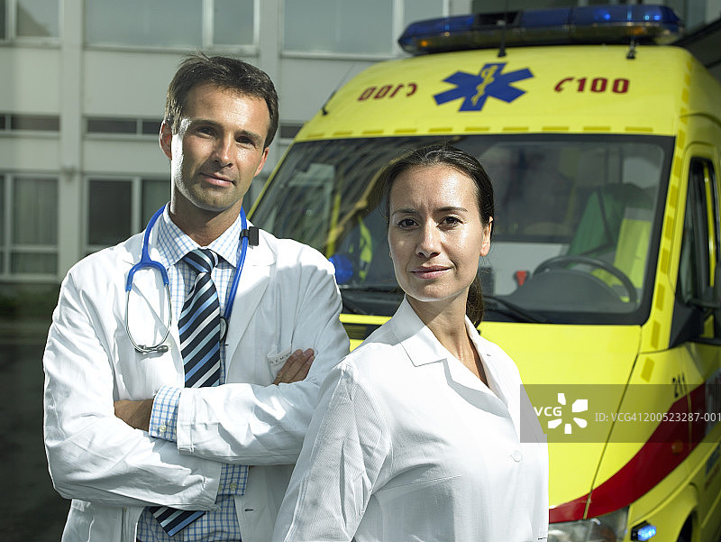 男医生和护士站在医院外的救护车旁，肖像图片素材