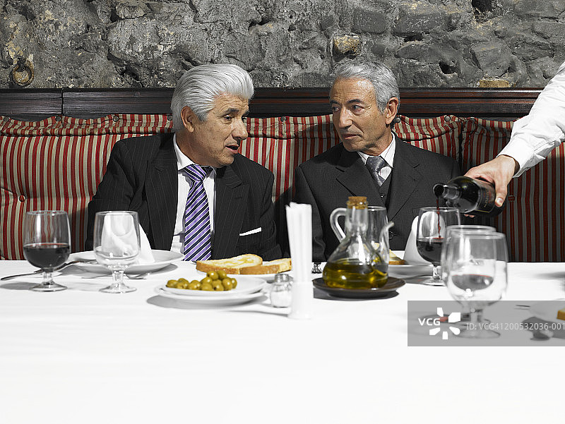 两位资深商人在餐厅聊天，服务员斟酒图片素材