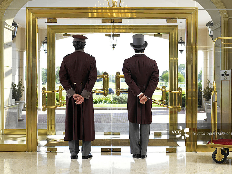 礼宾部和行李员站在酒店入口，后视图图片素材