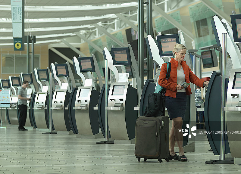 女子使用机场自动办理登机手续图片素材