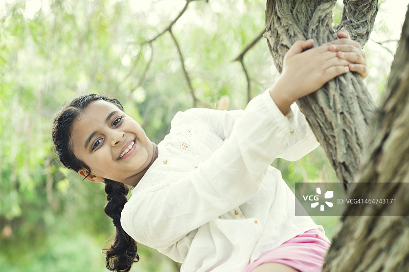 小女孩在公园的树上玩耍图片素材