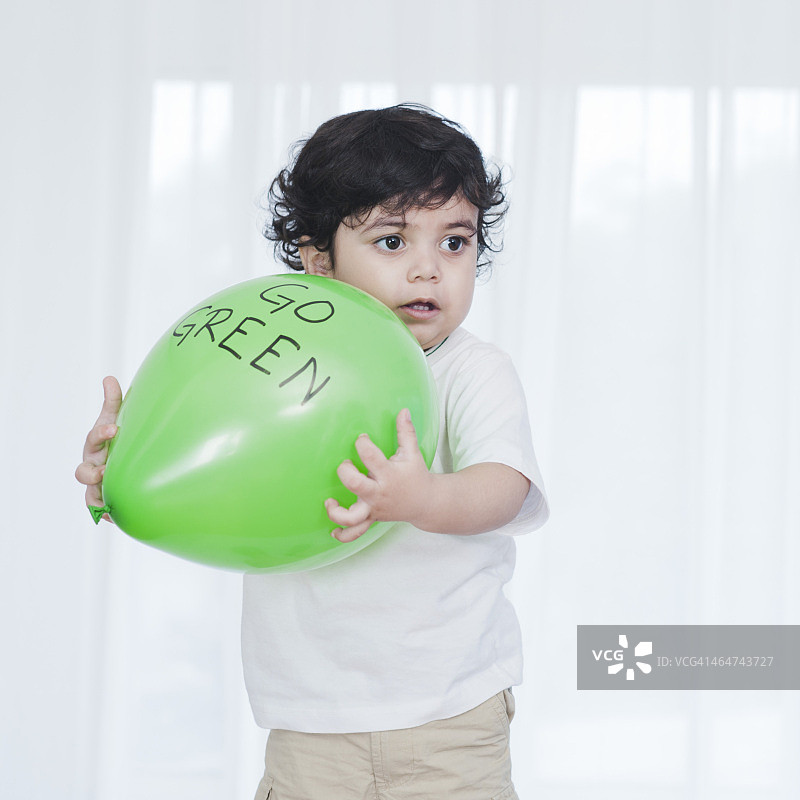 小男孩在玩一个绿色的气球图片素材