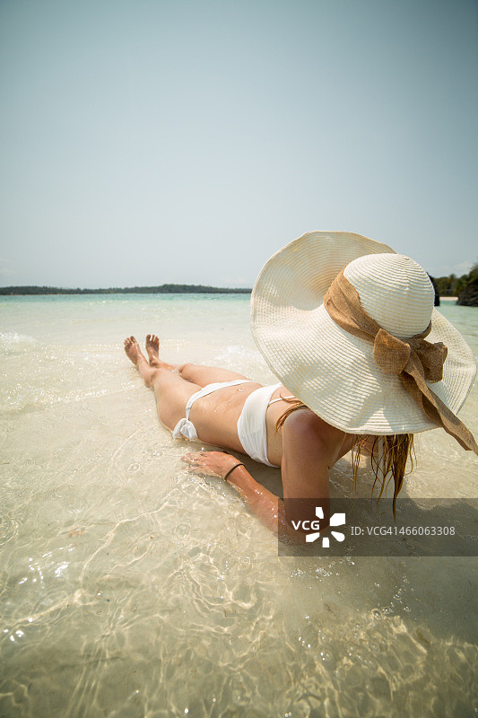 在热带度假的年轻女子躺在水里图片素材