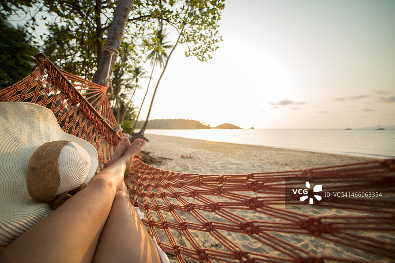 在热带海滩上的吊床上休息的女人图片素材