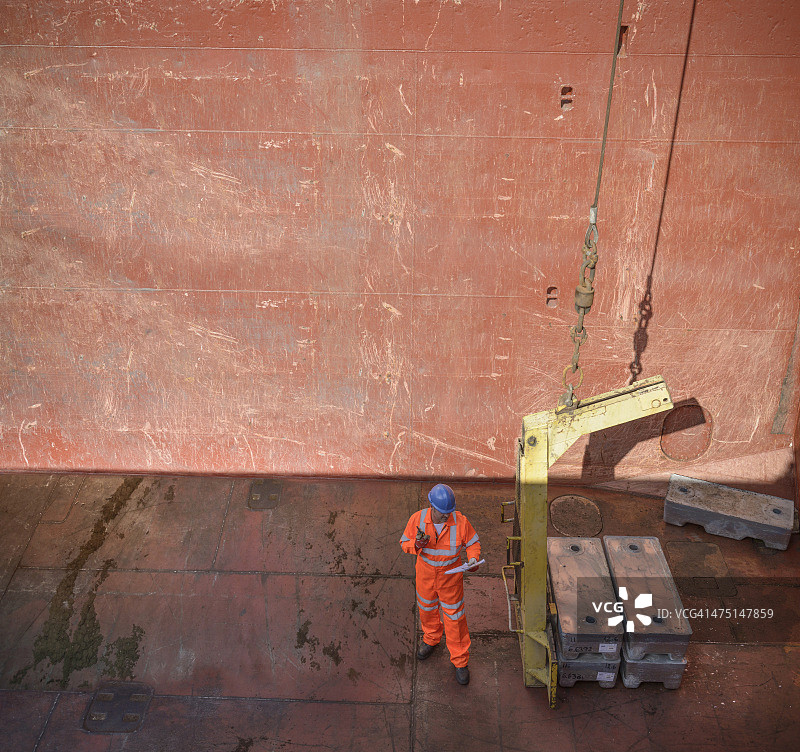 工人在船舱检查金属合金锭的高角度视图图片素材