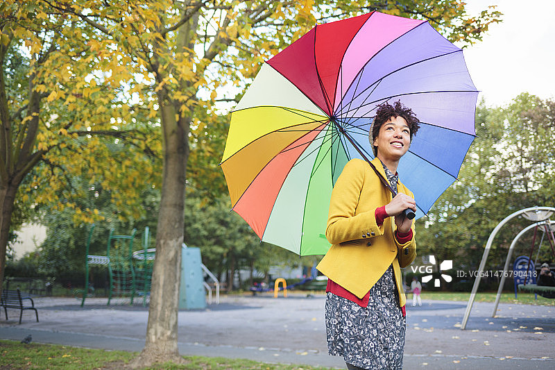 公园里的女人拿着五颜六色的雨伞。图片素材