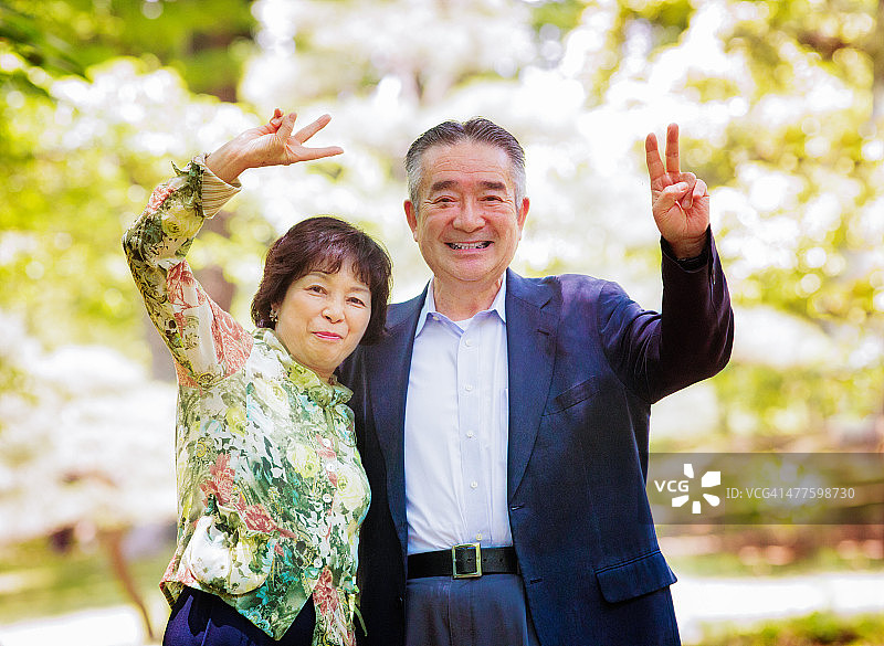 快乐的资深日本夫妇肖像与乐趣和平手势图片素材