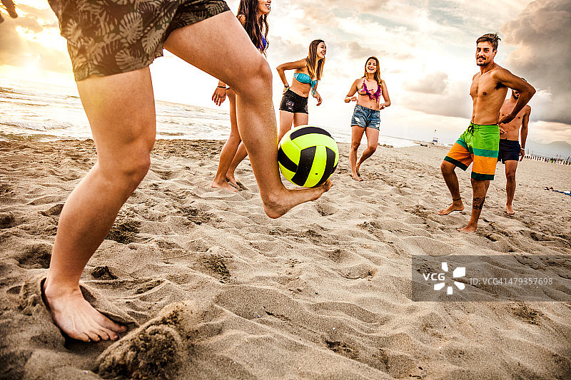朋友们在沙滩上踢足球图片素材