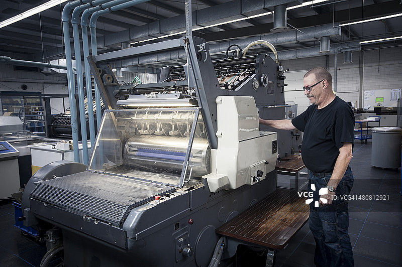 在印刷车间操作印刷机的工人图片素材