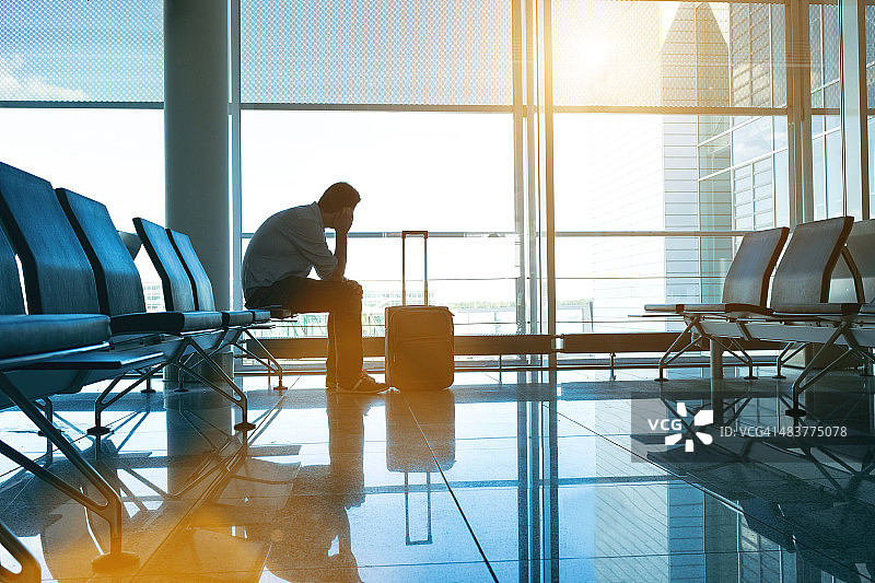 寂寞的乘客坐在空荡荡的机场等待他的航班图片素材