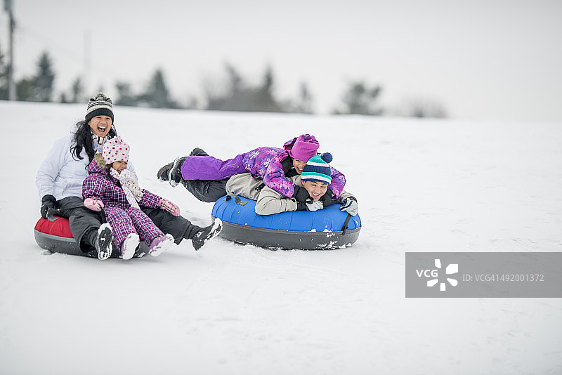 家庭愉快地乘坐内胎下雪山图片素材