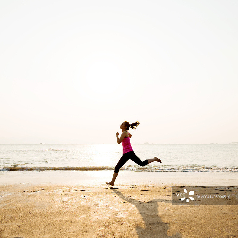日出时，一个女人在岸上慢跑图片素材