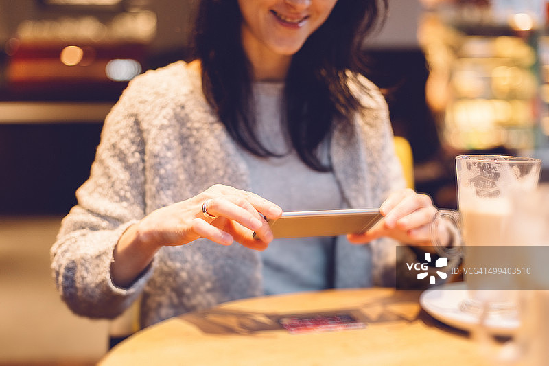 一个女人在咖啡馆里对着信用卡拍照图片素材