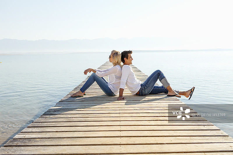 克罗地亚，一对年轻夫妇在海边的木板路上休息图片素材