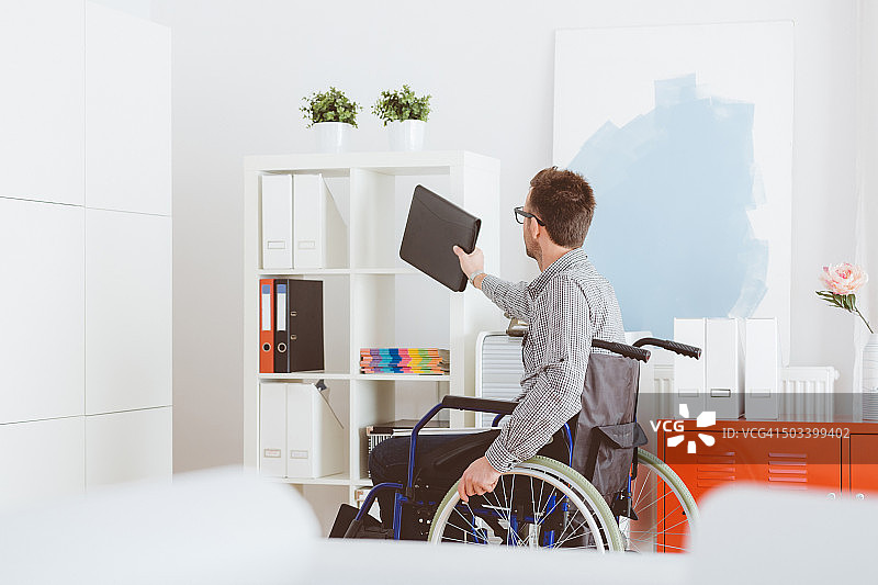 残疾人坐在家里的轮椅上图片素材