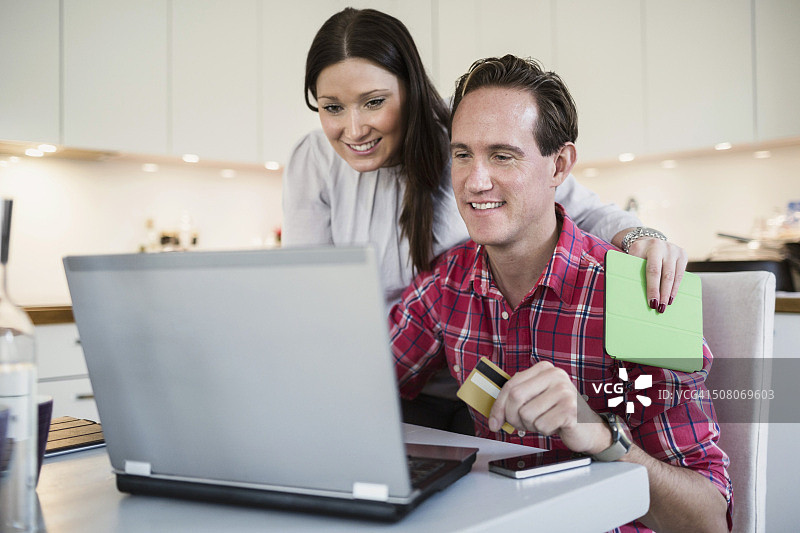 微笑的夫妇通过信用卡和笔记本电脑在网上购物图片素材
