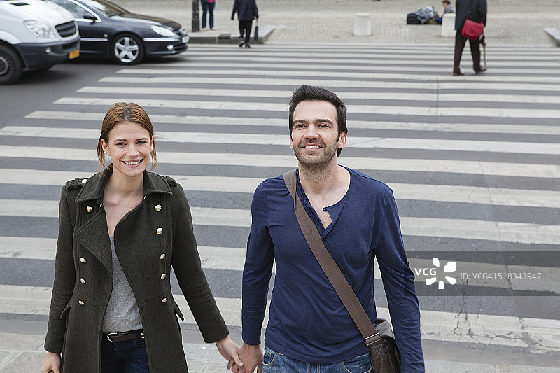 法国，巴黎，一对夫妇在人行横道上手牵手图片素材