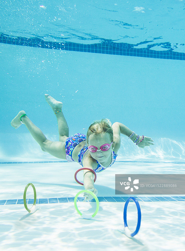 女孩(6-7)在水下收集潜水戒指图片素材