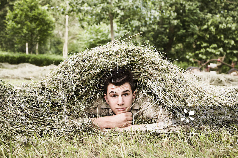 年轻人躺在一堆干草下面图片素材