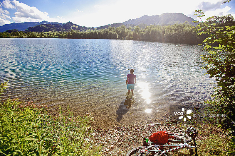 骑完自行车后站在水里的女人图片素材