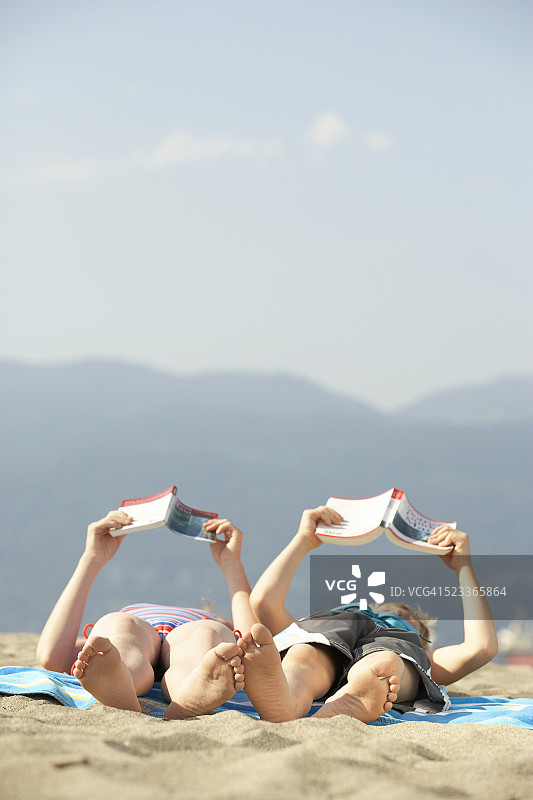 男孩和女孩在海滩上读书图片素材
