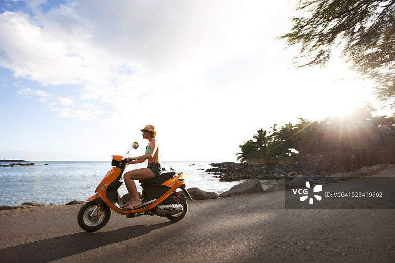 一名妇女骑着踏板车沿夏威夷海岸行驶图片素材