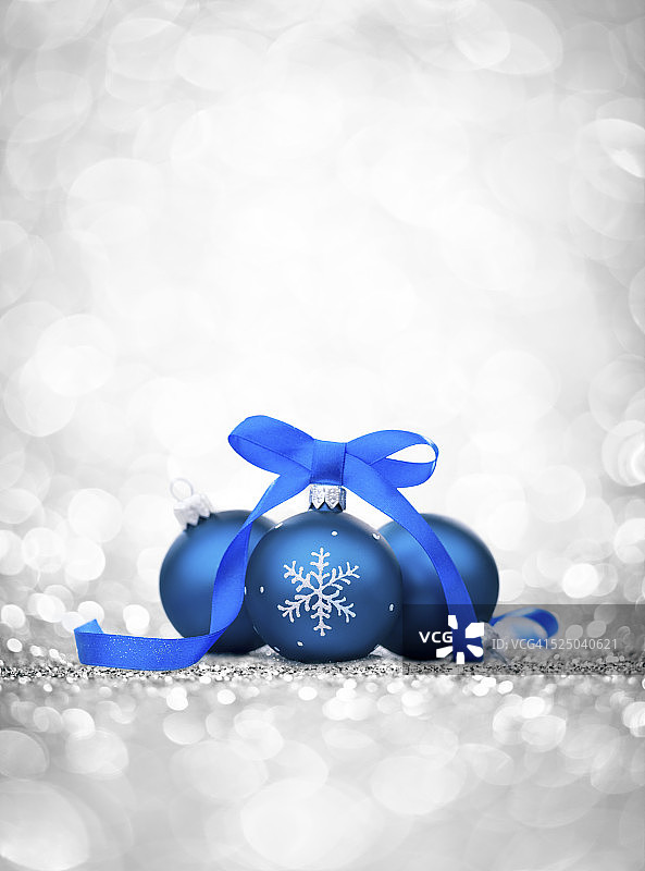 三个带缎带的蓝色小玩意，圣诞树上的装饰品和亮片图片素材