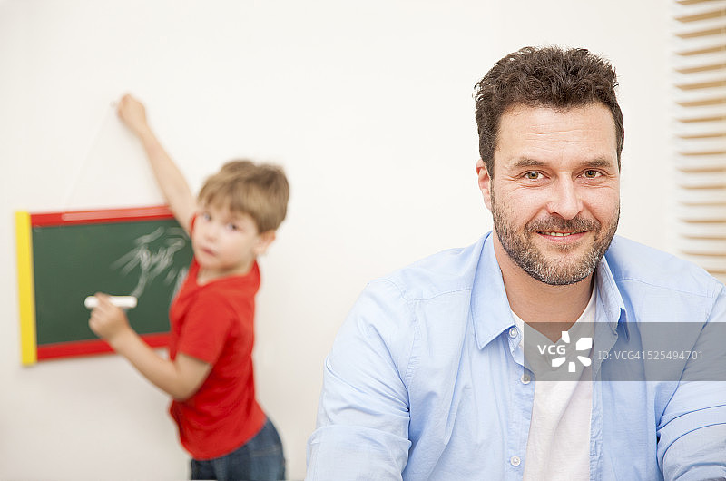微笑的父亲和他的小儿子在背景的肖像图片素材