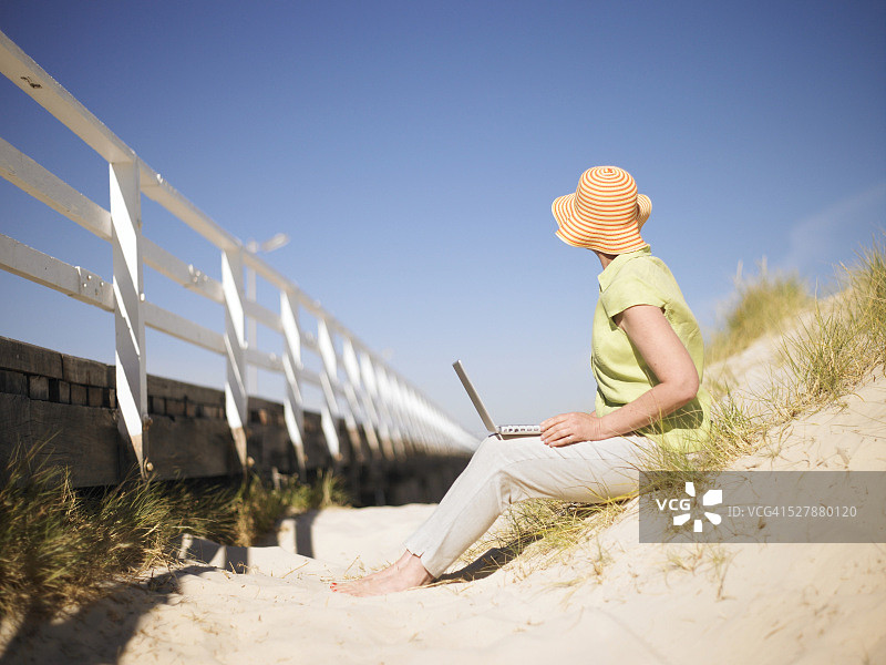 坐在沙滩上用笔记本电脑的女人图片素材