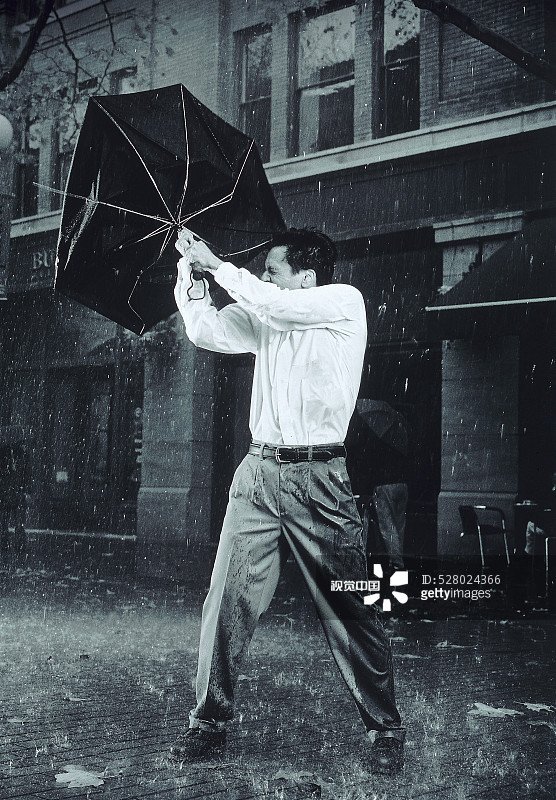 一名男子试图拿着伞以防被风吹走图片素材