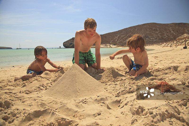 圣埃斯皮里图岛洛斯群岛国家海洋公园，三个男孩在水边的沙滩上玩耍;墨西哥下加利福尼亚的拉巴斯图片素材